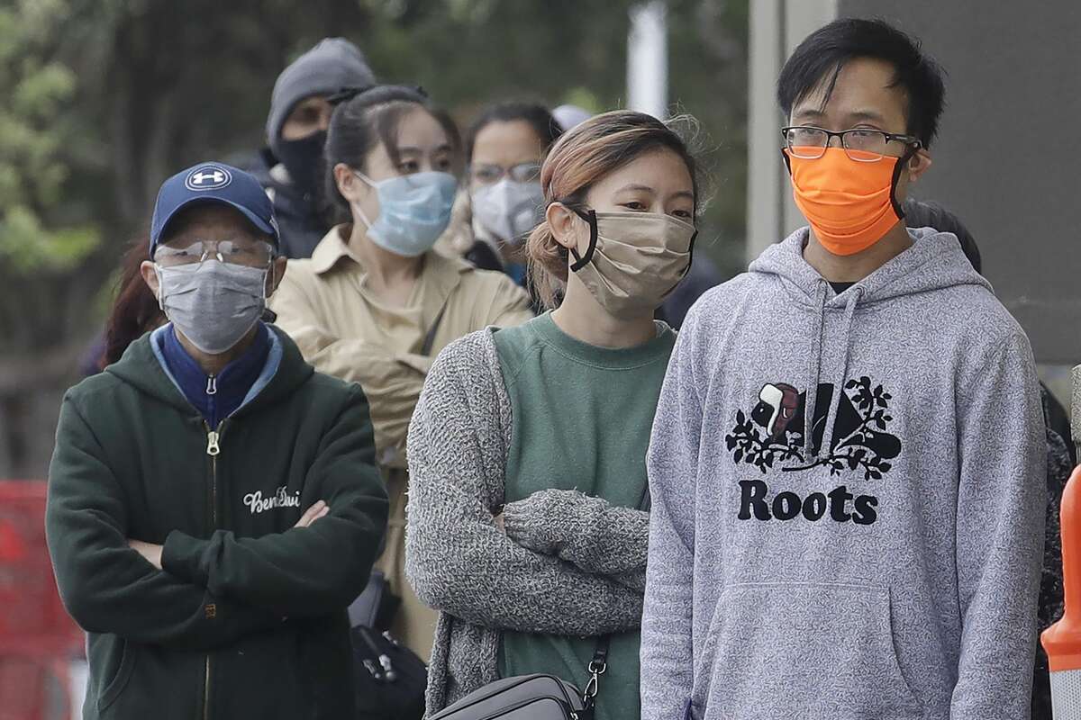 A line of people wearing face masks wait to enter a Trader Joe's grocery store during the coronavirus outbreak in San Francisco, Saturday, May 9, 2020.