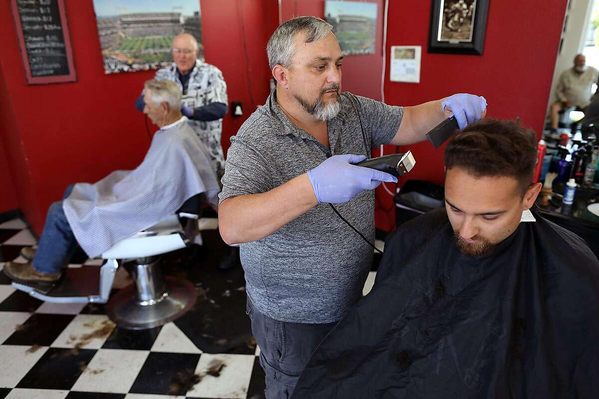 Wes Heryford, center, owner, who has been cutting hair for over 24-years, works on Ben Martin, 25, at Butte House Barber Shop on Wednesday, May 6, 2020, in Yuba City, Calif. Heryford closed his business on March 22 due to the coronavirus and opened back up on May 5. (Gary Coronado/Los Angeles Times/TNS)