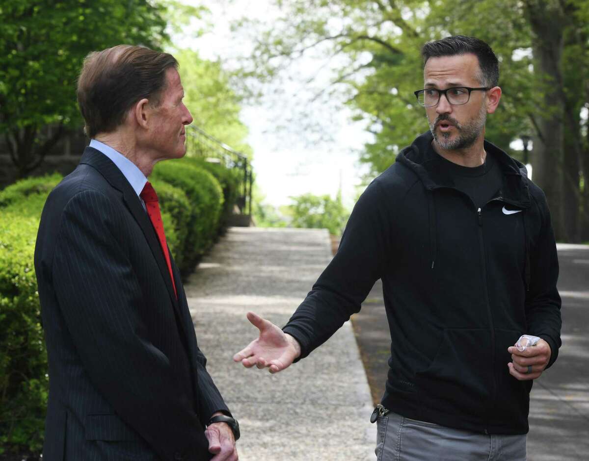 The Rev. Patrick Collins, right, and U.S. Sen.. Richard Blumenthal, D-Conn., speak at First Congregational Church of Greenwich last May. Collins put flags in front of the church to mark the number of COVID deaths in Connecticut. That number has now exceeded 500,000 nationwide.