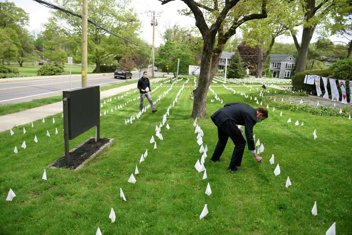 The Rev. Patrick Collins, left, and U.S. Sen.. Richard Blumenthal, D-Conn., place flags in memory of the Connecticut lives lost from coronavirus at First Congregational Church of Greenwich last May.