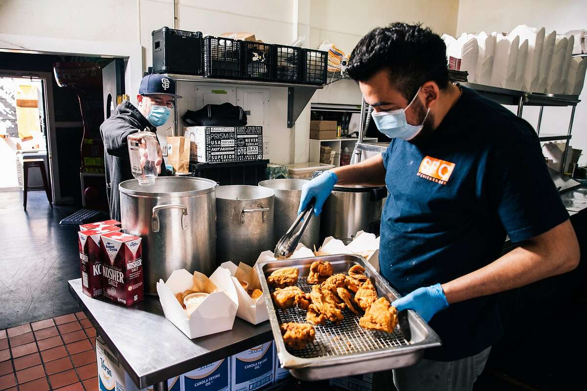 Christian Ciscle, chef-owner of SF Chickenbox, left, prepares a pickle brine as Pedro Giron distributes fried chicken into to-go boxes at SF Chickenbox in San Francisco, Calif. on Friday, May 15, 2020. The fried chicken, part of a batch of to-go meals, is part of a partnership with SF New Deal, a non-profit formed in response to the COVID-19 pandemic where the organization provides relief to small businesses by ordering meals from restaurants and delivering them to at-risk community members in San Francisco.