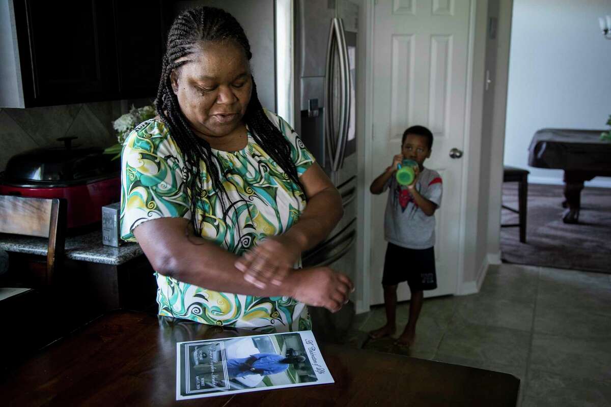Shelia Hendrix stands with her grandson, Tyree Heath, in her kitchen looking at a photo of her son, Edison "Tater" Hendrix, 33, on Thursday, May 7, 2020, in Houston. Hendrix remembers her son, whom she nicknamed "Tater" as a baby, as a big-hearted truck driver who loved getting behind the wheel of his 2011 Chevy Camaro in his free time. After he followed his father into the trucking industry, he persuaded friends to join him to get them off the street.