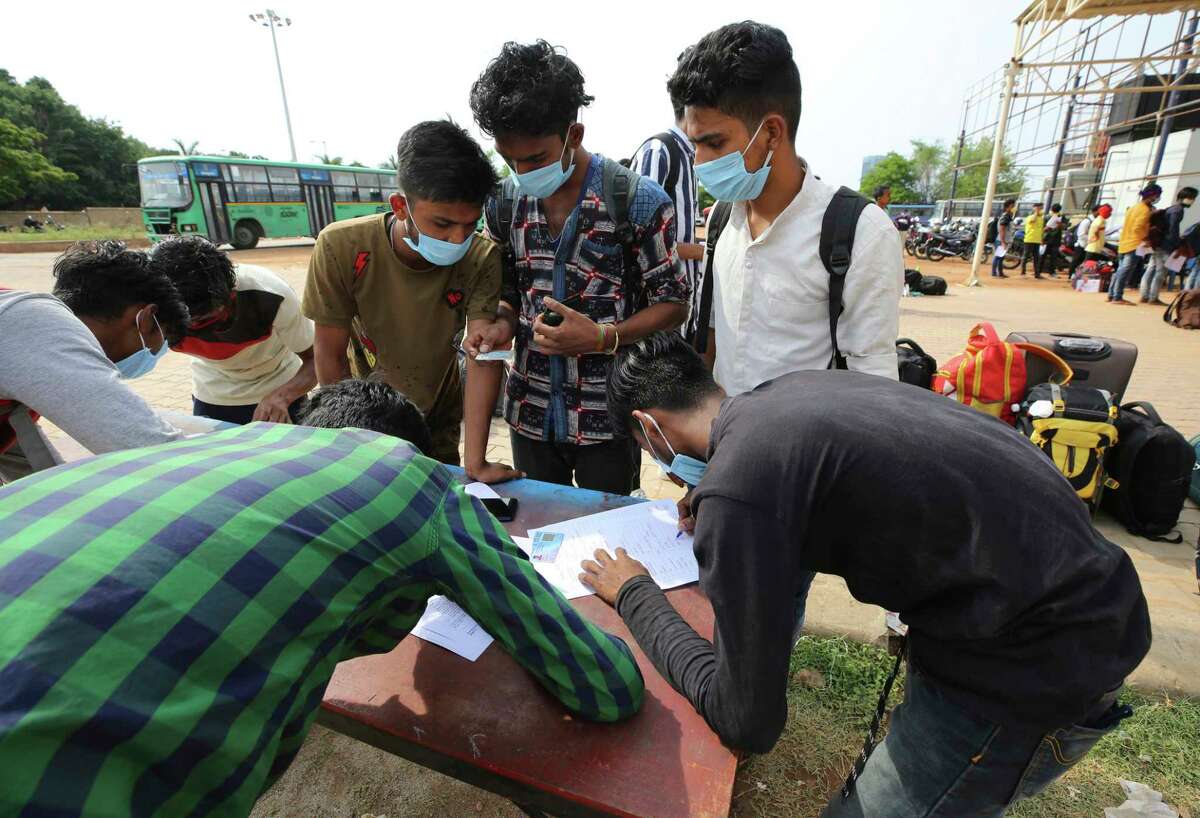 Stranded migrant workers fill in their details for registration to take a special train home during extended lockdown to curb the spread of new coronavirus, in Bangalore, India, Monday, May 18, 2020. India has recorded its biggest single-day surge in new cases of coronavirus. The surge in infections comes a day after the federal government extended a nationwide lockdown to May 31 but eased some restrictions to restore economic activity and gave states more control in deciding the nature of the lockdown.