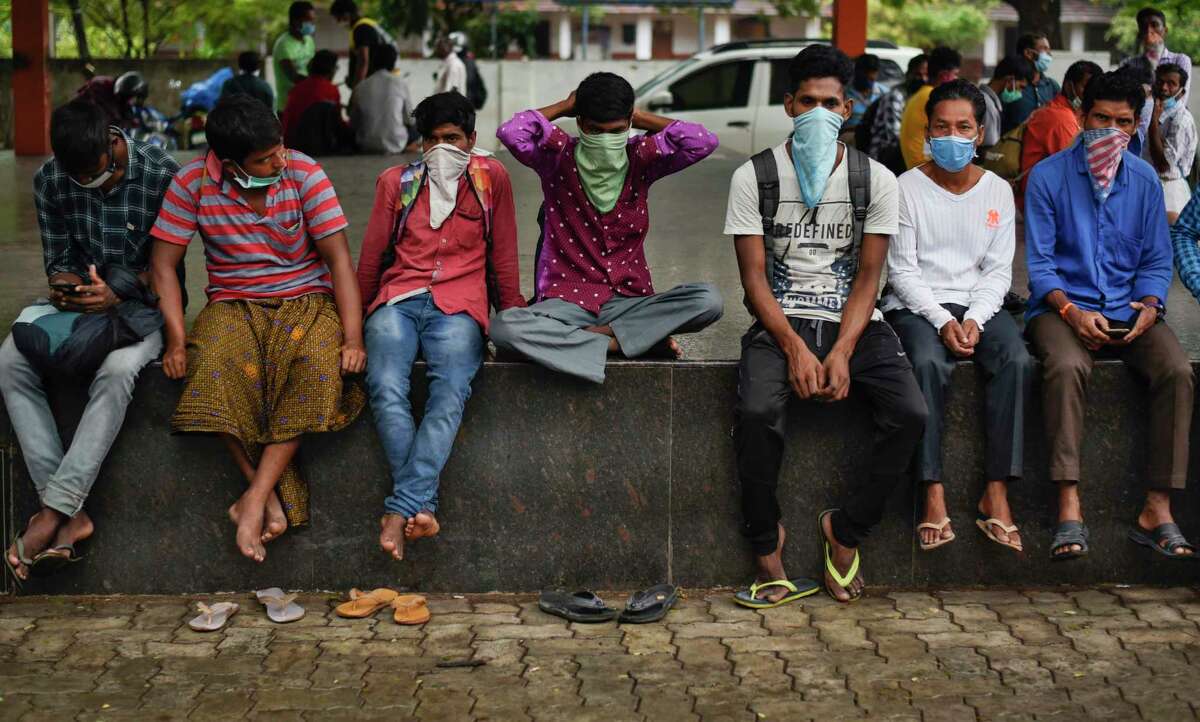 Migrant workers who have yet been unable to return to their home states in north India sit wearing masks at a town square during lockdown in Kochi, In the southern Indian state of Kerala, Tuesday, May 19, 2020. The number of coronavirus cases in India has surged past 100,000, with most of the cases being in major cities. But rural villages across India are also seeing an increase in cases with the return of hundreds of thousands of migrant workers who left cities and towns where they were abandoned by their employers after having toiled for years building homes and roads.