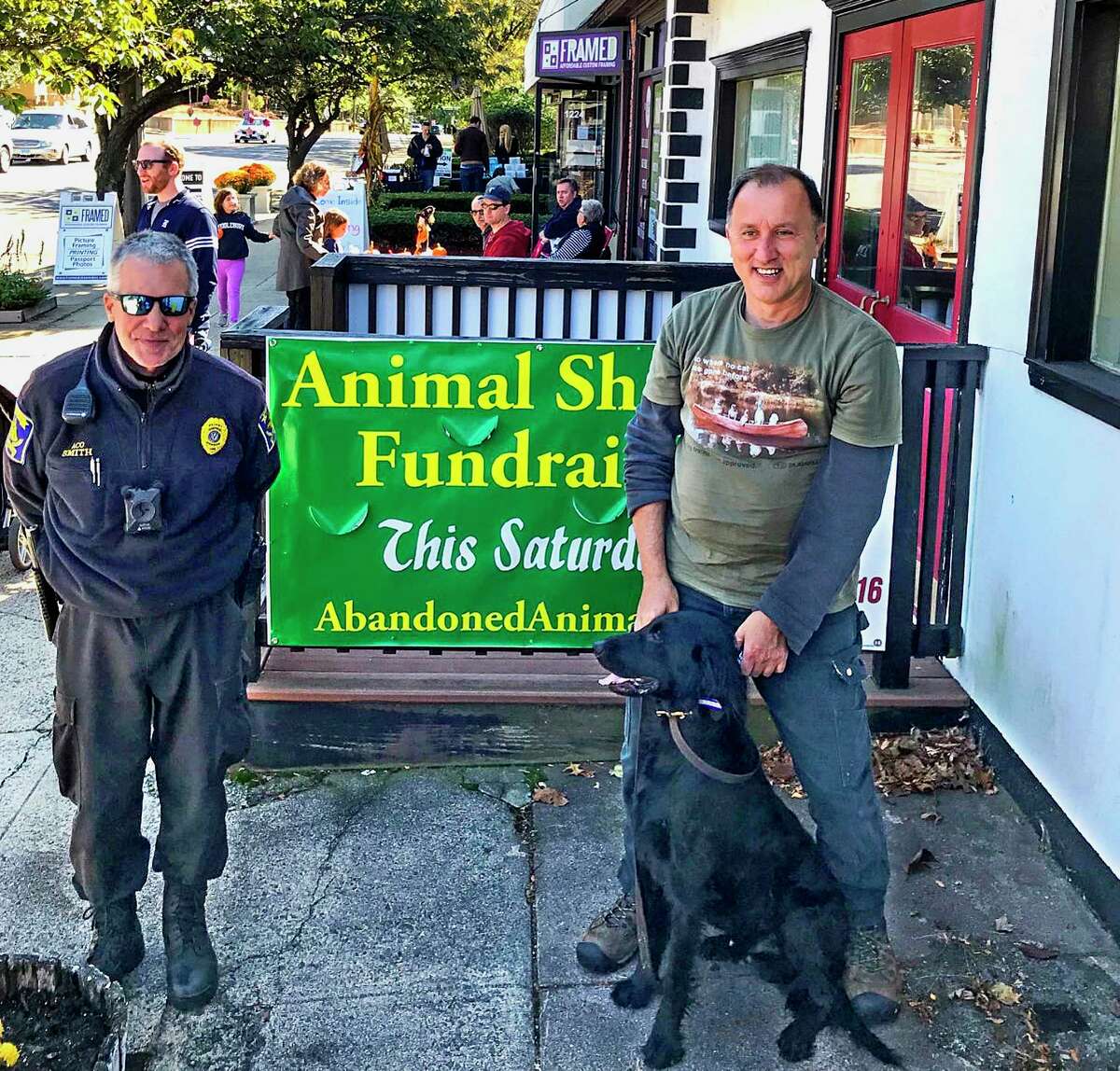 Hamden Animal Control Officer Chris Smith, left, with Gimme Shelter President Leonard Young and Seamus, a flat-coat retriever, at the Whitneyville Wine Walk on Oct. 5, 2019. That event spearheaded a $2,436 donation to Hamden’s Animal Shelter Gift Fund.
