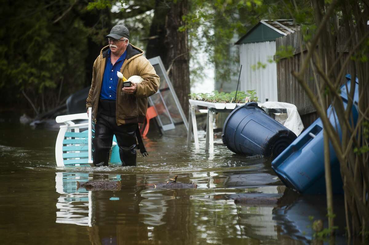Mark Musselman brings a chair to the front of his house from the back yard, wading through floodwater, Tuesday, May 19, 2020. An evacuation order was released the night before for residents of Sanford and Wixom Lakes, warning of "imminent dam failure." "We're all safe, that's the main thing," said Mark's wife, Ruth Musselman. (Katy Kildee/kkildee@mdn.net)