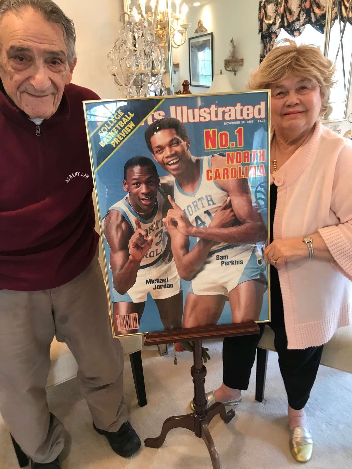 ohn and Marlene Elacqua pose with the Sports Illustrated cover signed by Michael Jordan and Sam Perkins, who lived with the Elacquas his senior year at Shaker High School in 1979-80.