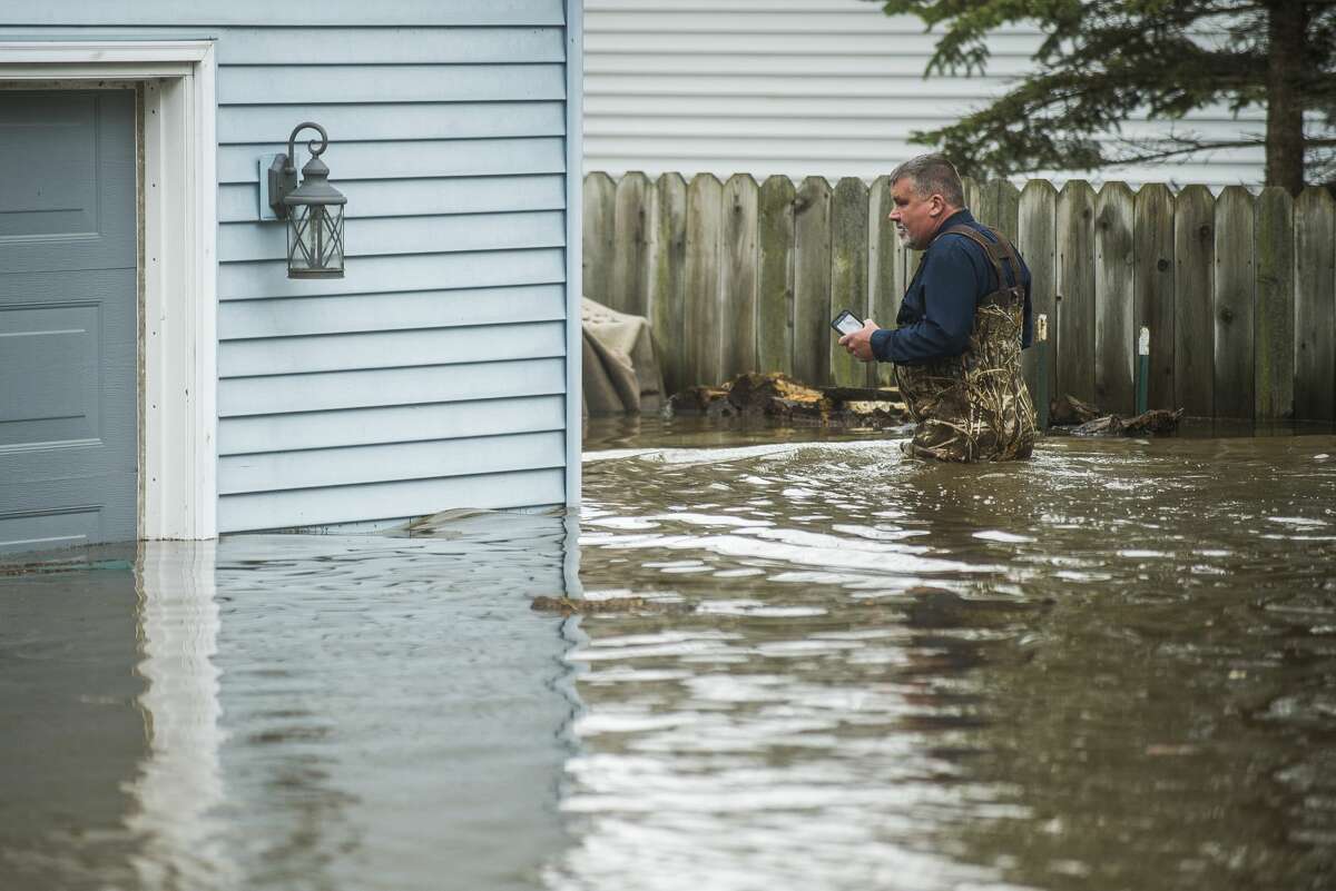 Tom Marciniak wades through floodwater to assess the damage to his home on Red Oak Drive on Wixom Lake Tuesday, May 19, 2020 in Beaverton. (Katy Kildee/kkildee@mdn.net)