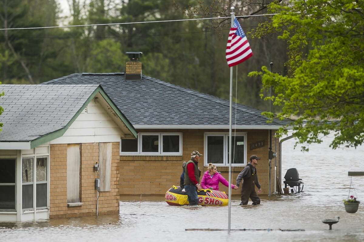 People help each other travel from one home to another using an inflatable raft on Oakridge Road on Wixom Lake Tuesday, May 19, 2020 in Beaverton. (Katy Kildee/kkildee@mdn.net)