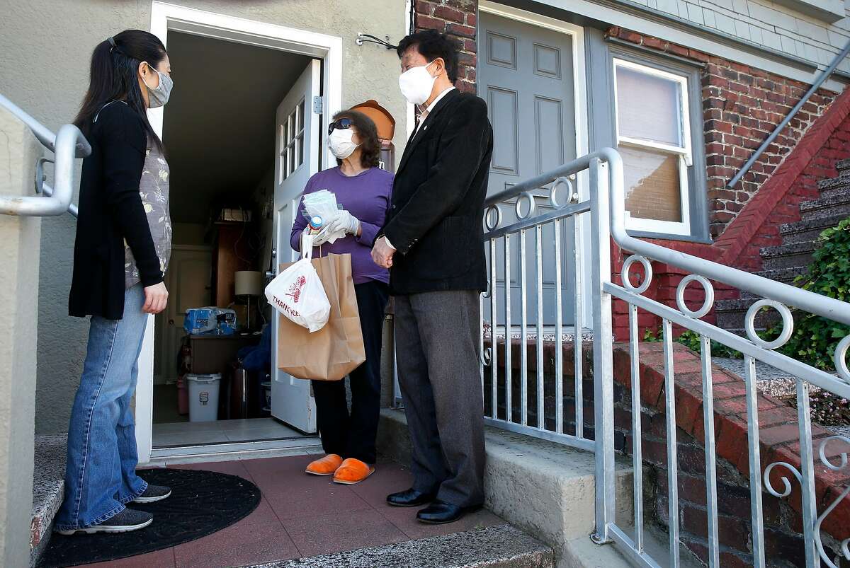 Communities As One co-founder Josephine Zhao (left) and Tommy Tang (right) delivers food, medication and face masks to Annie Chu in the Sunset district in San Francisco, Calif. on Tuesday, May 19, 2020. Communities As One is distributing PPE, groceries and other essential items to restaurant workers and Asian seniors who are at a greater risk of contracting the COVID-19 coronavirus.
