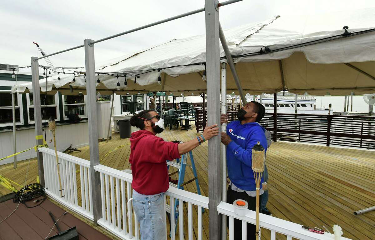 Employees with Norwalk Tent Co. raise a tent at Sunrise Grille as restaurants prepare their outdoor seating for reopening Tuesday, May 19, 2020, in Norwalk, Conn. Connecticut governor allowed the reopening of eateries with outdooor seating.