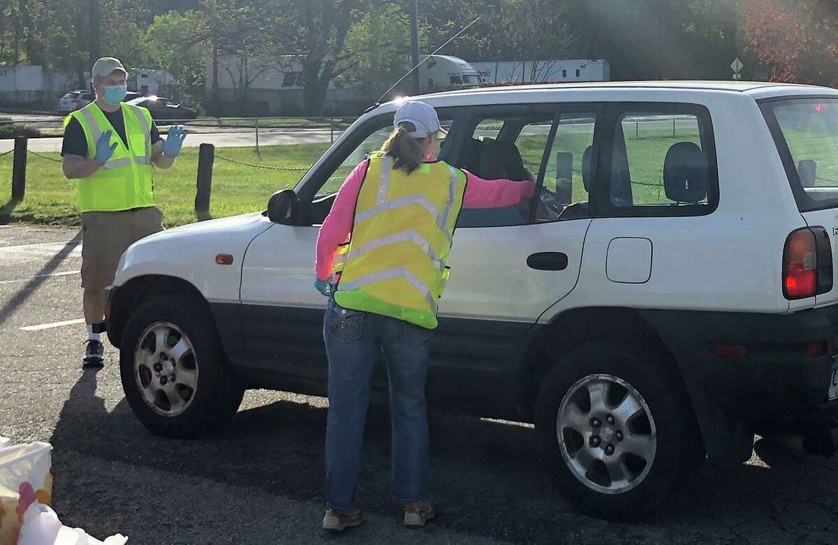 Spectrum/The Rotary Club of New Milford played host to a mask giveaway May 16, 2020 at the John Pettibone Community Center. A bag with five disposable masks was given to each vehicle that stopped by. The event is co-sponsored by Masks for CT, the Jewish Federation of Greater New Haven, Masks for Heroes, Housatonic Business Alliance, Goatboy Soaps, On the Mend, Webster Bank and WFSB3. Above, Rotarian Ralph Williams directs vehicles in line as Melissa Hladeck-Alford tosses a bag of masks into a car. . Spectrum/The Rotary Club of New Milford played host to a mask giveaway May 16, 2020 at the John Pettibone Community Center. A bag with five disposable masks was given to each vehicle that stopped by. The event is co-sponsored by Masks for CT, the Jewish Federation of Greater New Haven, Masks for Heroes, Housatonic Business Alliance, Goatboy Soaps, On the Mend, Webster Bank and WFSB3. Above, Rotarian Ralph Williams directs vehicles in line as Melissa Hladeck-Alford tosses a bag of masks into a car.