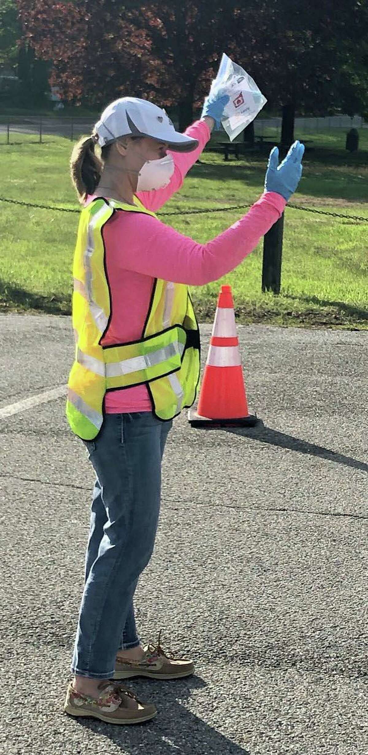 Melissa Hladek-Alford, a member of the New Milford Rotary Club, signals to a motorist where to stop for a bag of masks.