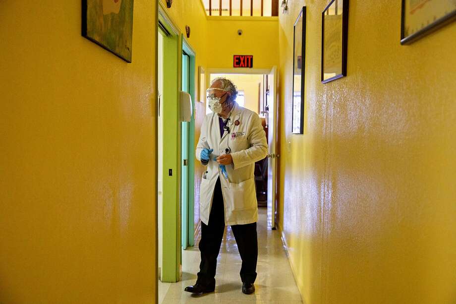 Dr. Carlos Ramírez enters an exam room to see a patient at his storefront medical clinic in the Fruitvale neighborhood of Oakland. He charges an $80 flat fee for a consultation and when they can’t afford the care, he often treats them for free. Photo: Jessica Christian / The Chronicle