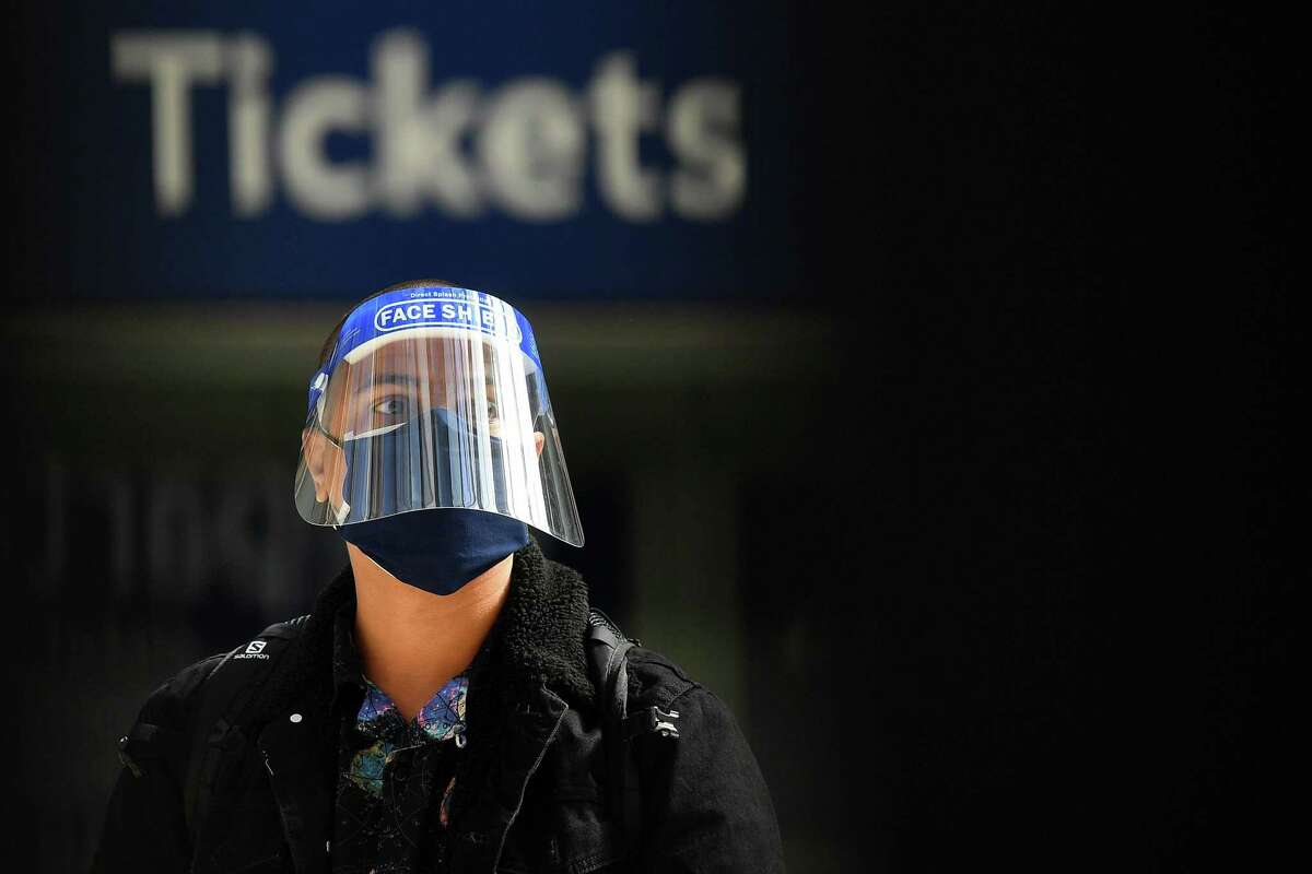A commuter wearing PPE (personal protective equipment), including a face shield and a face mask as a precautionary measure against COVID-19, walks past a ticket booth at Waterloo Train station in central London on May 18.