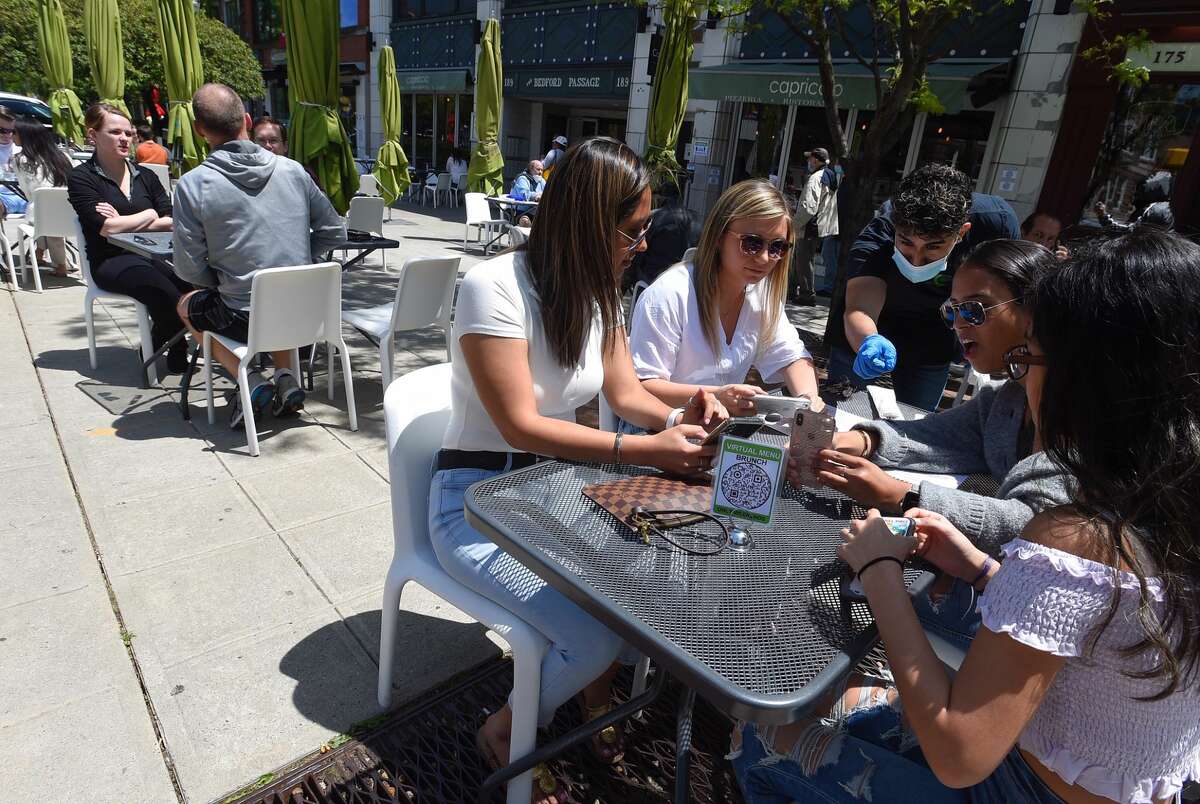 Patrons set up the iPhones with a virtual menu at Capriccios in Stamford. The restaurant is one of several to reopen with outdoor dining service.