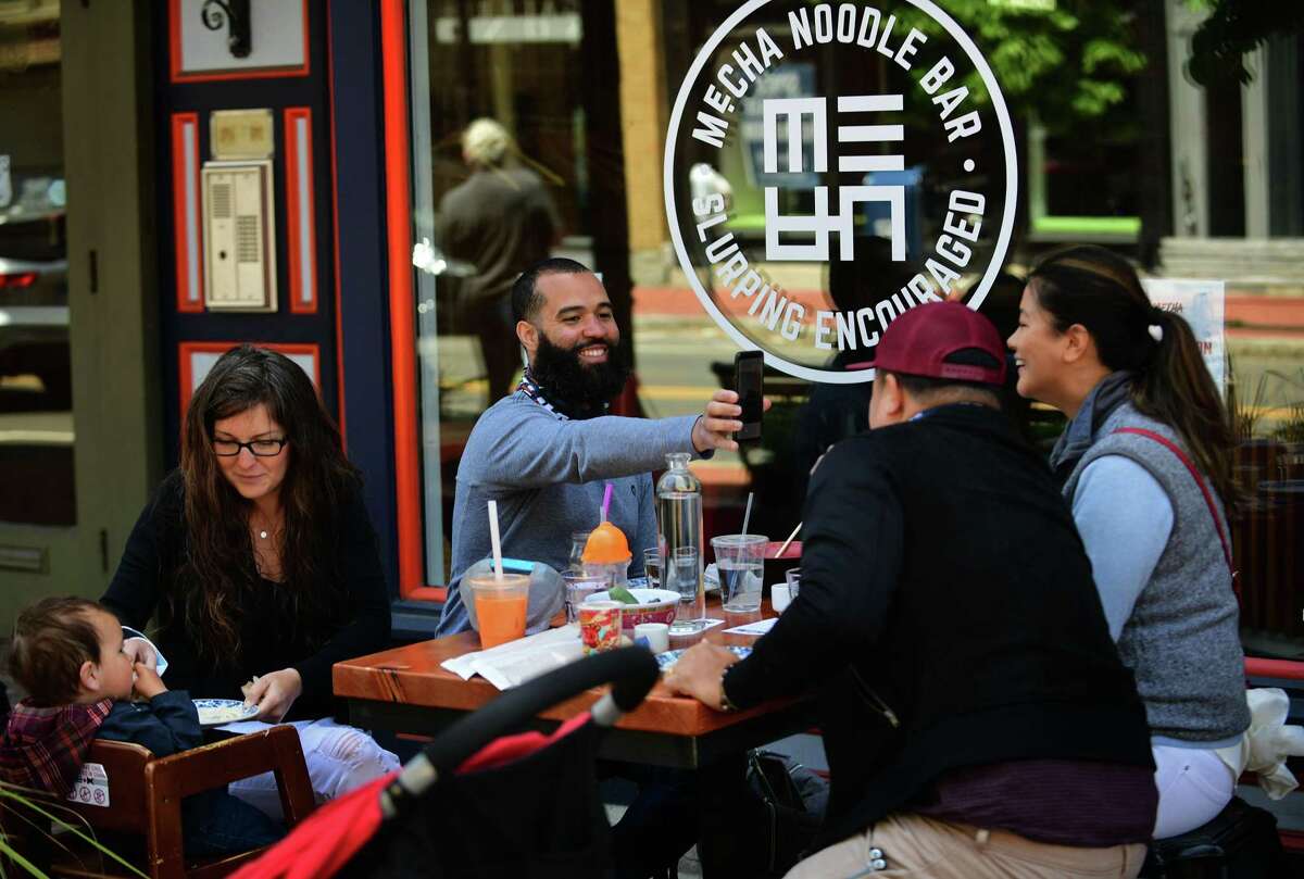 Local residents get out to enjoy the town Wednesday , including patrons at Mecha Noodle Bar on Washington Street in Norwalk during the limited reopening after the quarantine due to the coronavirus outbreak.