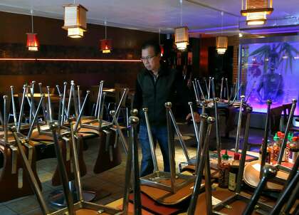 Green Papaya owner Thai Van walks through his temporarily closed restaurant in San Francisco.