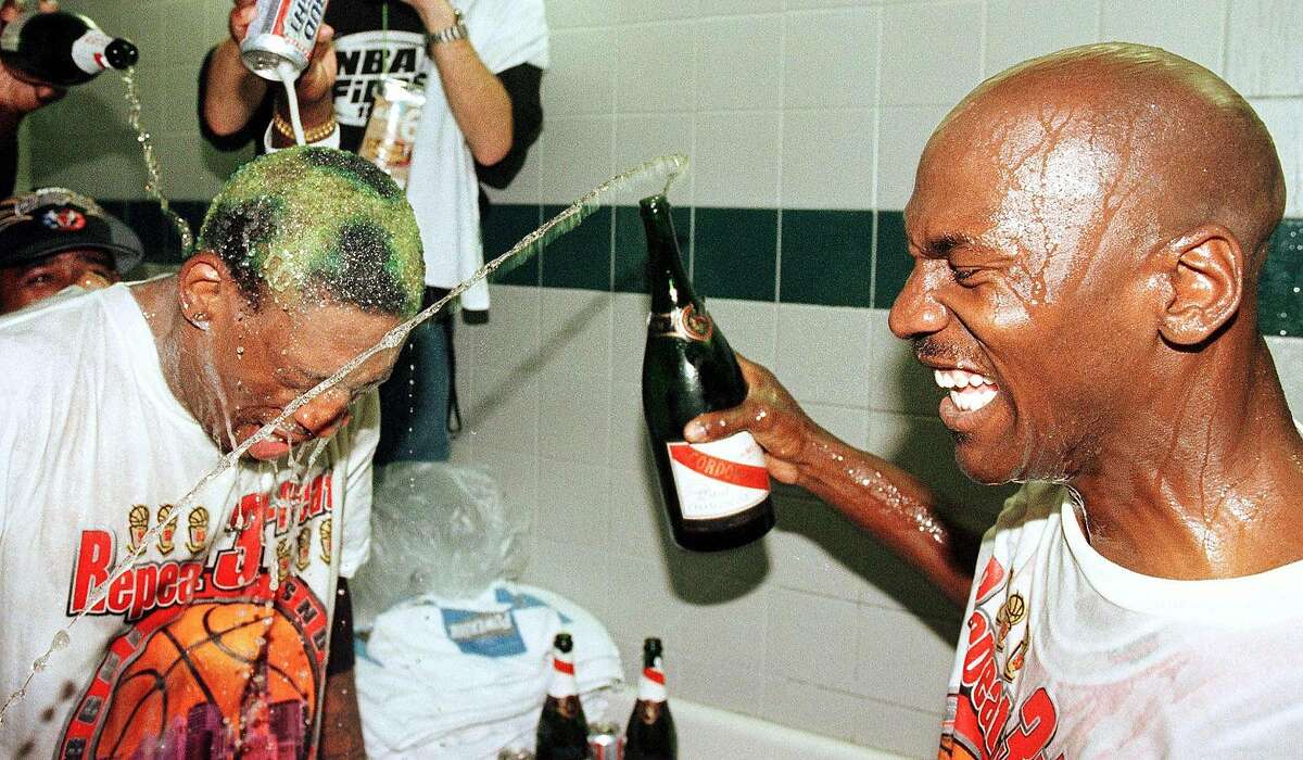 Dennis Rodman, left, of the Chicago Bulls has beer and Champagne poured on his head by teammate Michael Jordan, right, and others on June 14, 1998, after winning the NBA championship against the Utah Jazz at the Delta Center in Salt Lake City. (Mike Nelson/AFP/Getty Images/TNS)