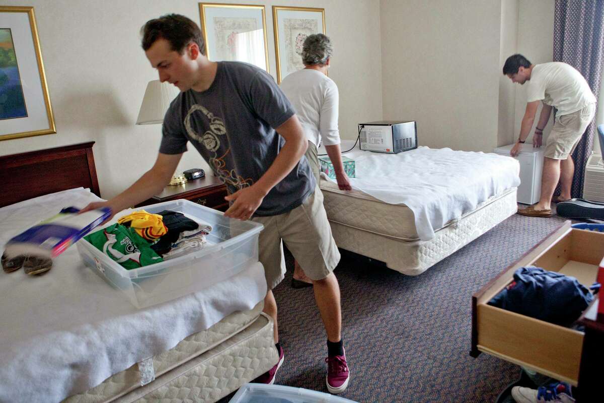 At left Benjamin North, 20, of Woodbury, a senior who will soon graduate, unpacks his clothes onto his bed at Nathan Hale Inn on the campus of the University of Connecticut Friday, August 24, 2012.