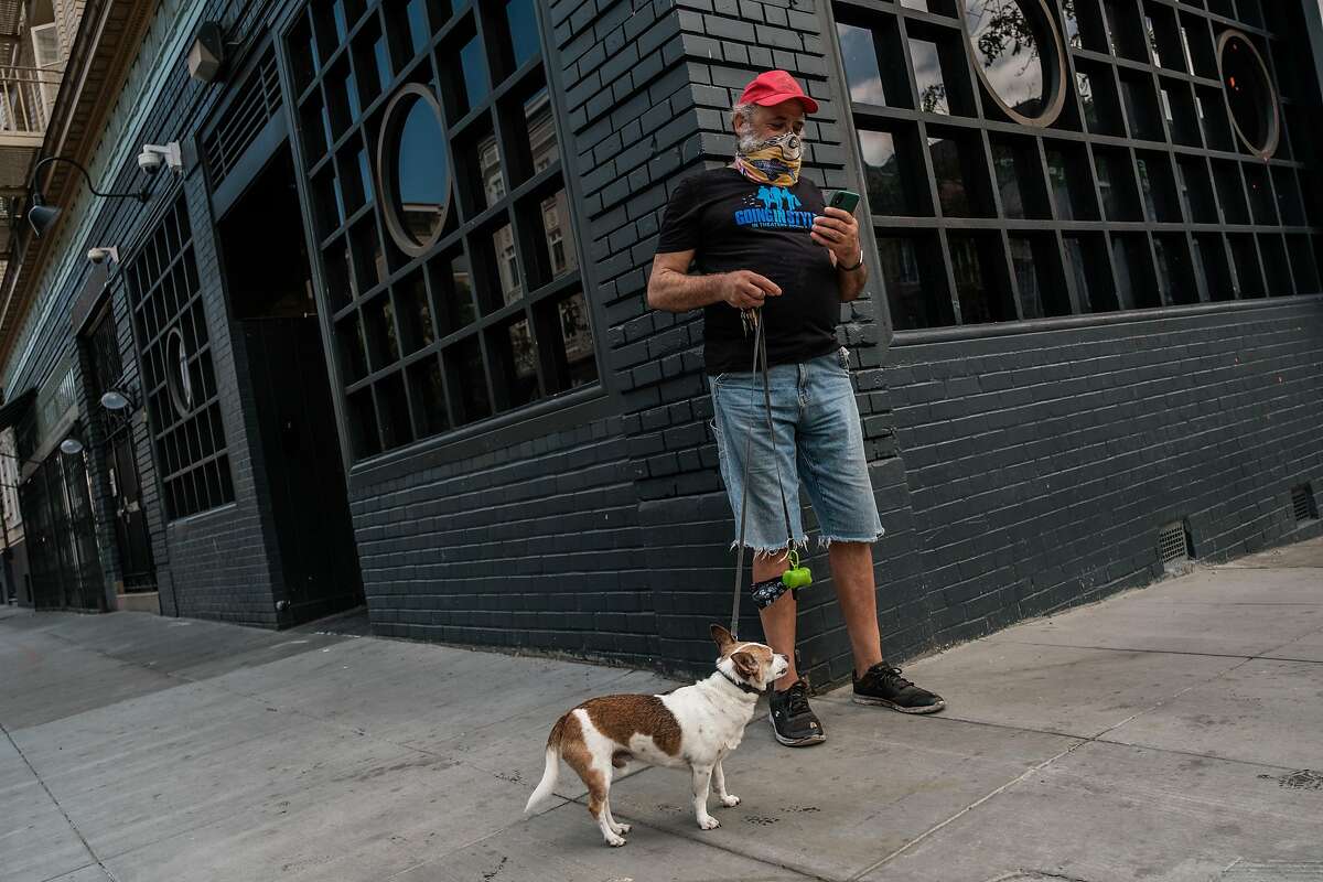 CJ Peoples pauses while with his dog, Mister, to check his email after collecting his groceries from Project Open Hand in San Francisco on Wednesday, May 20, 2020.