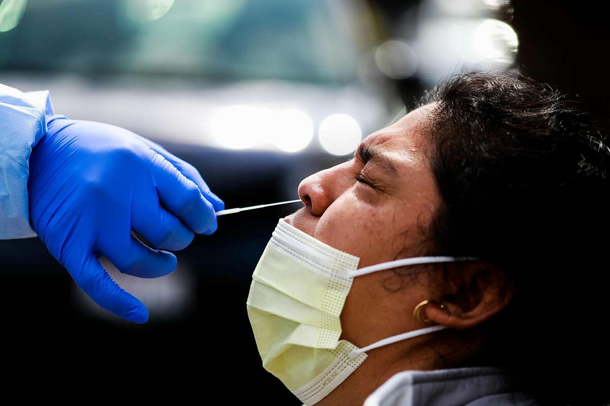 Dentist Dr. Marco Reyes (left) gives patient Marta Munoz (right) a Covid-19 test in San Francisco, California on Thursday, April 9, 2020.A small tent in the Southeast Health Center parking lot was serving as an alternative testing site for potential COVID-19 cases. Patients who are tested have been pre-screened by a health care provider.