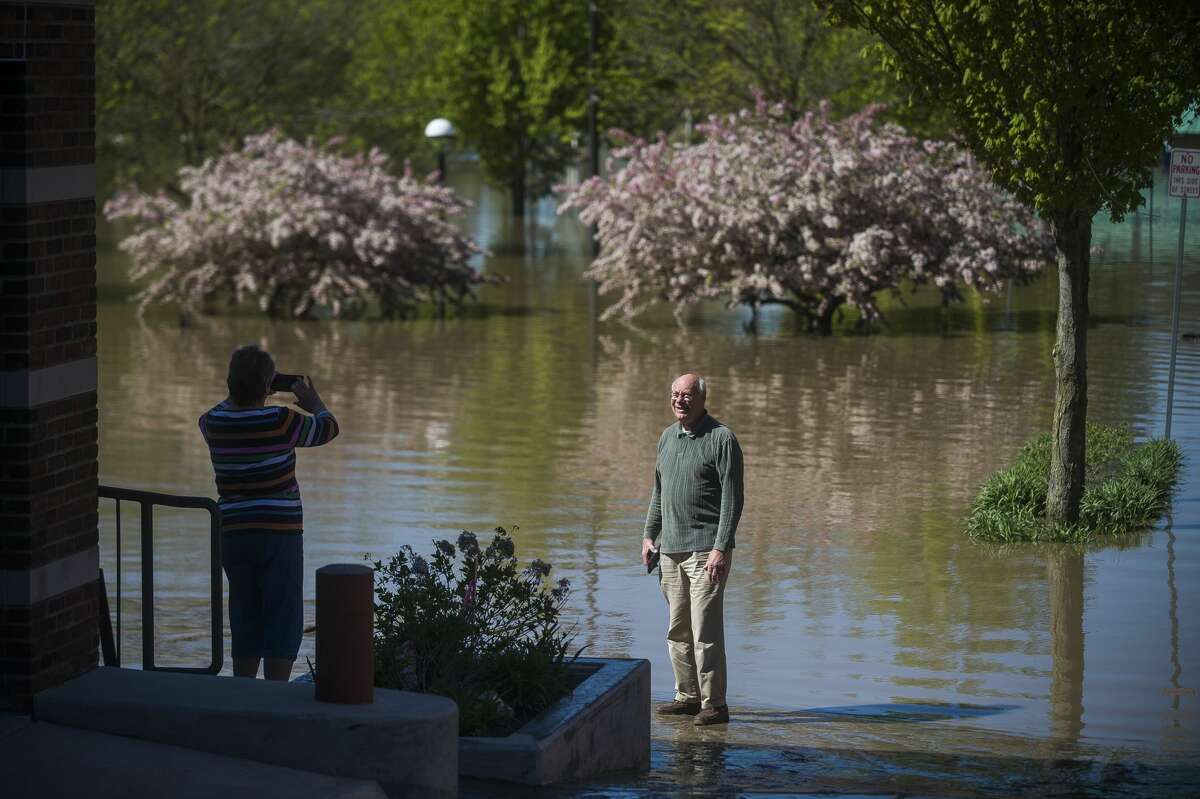 A man poses for a photo near floodwater in downtown Midland Thursday morning. (Katy Kildee/kkildee@mdn.net)