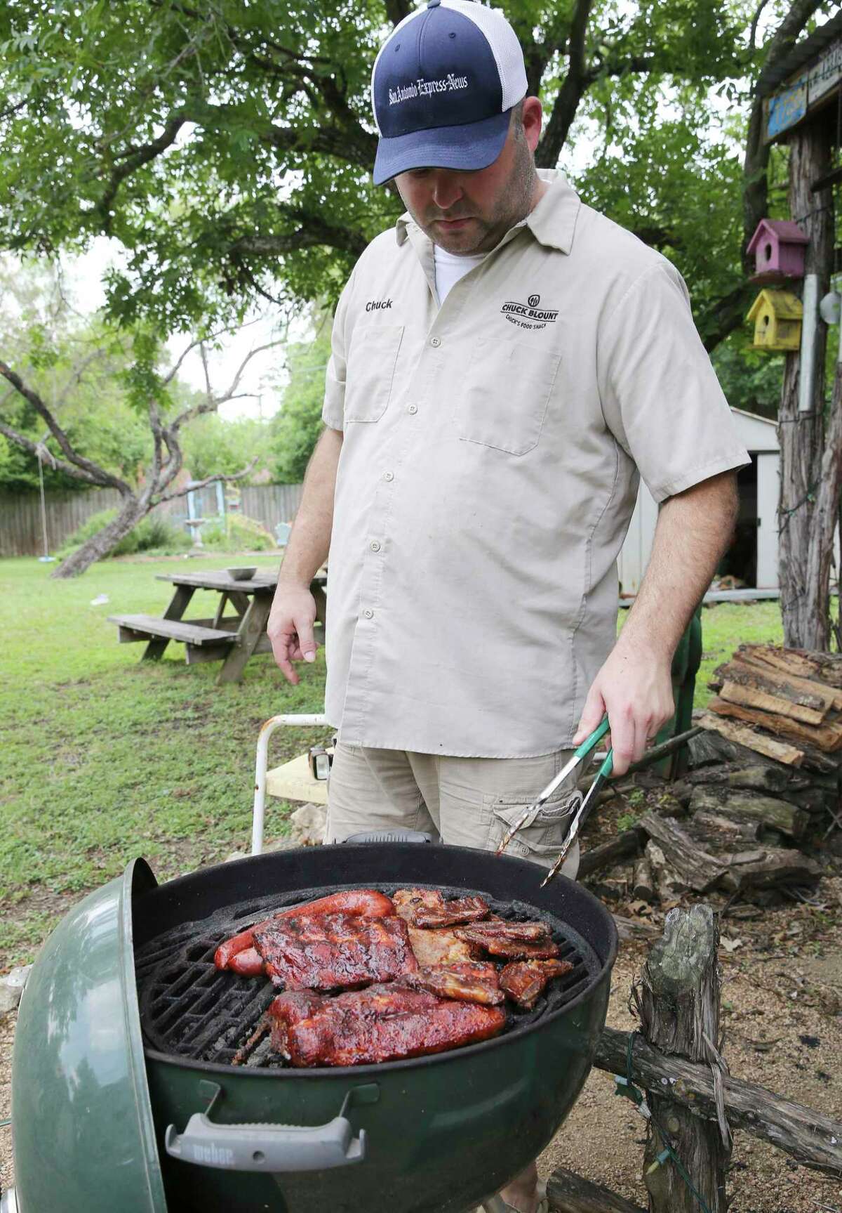 Chuck Blount turns meats over on the grill after applying layers of the barbecue sauces that he recommends.