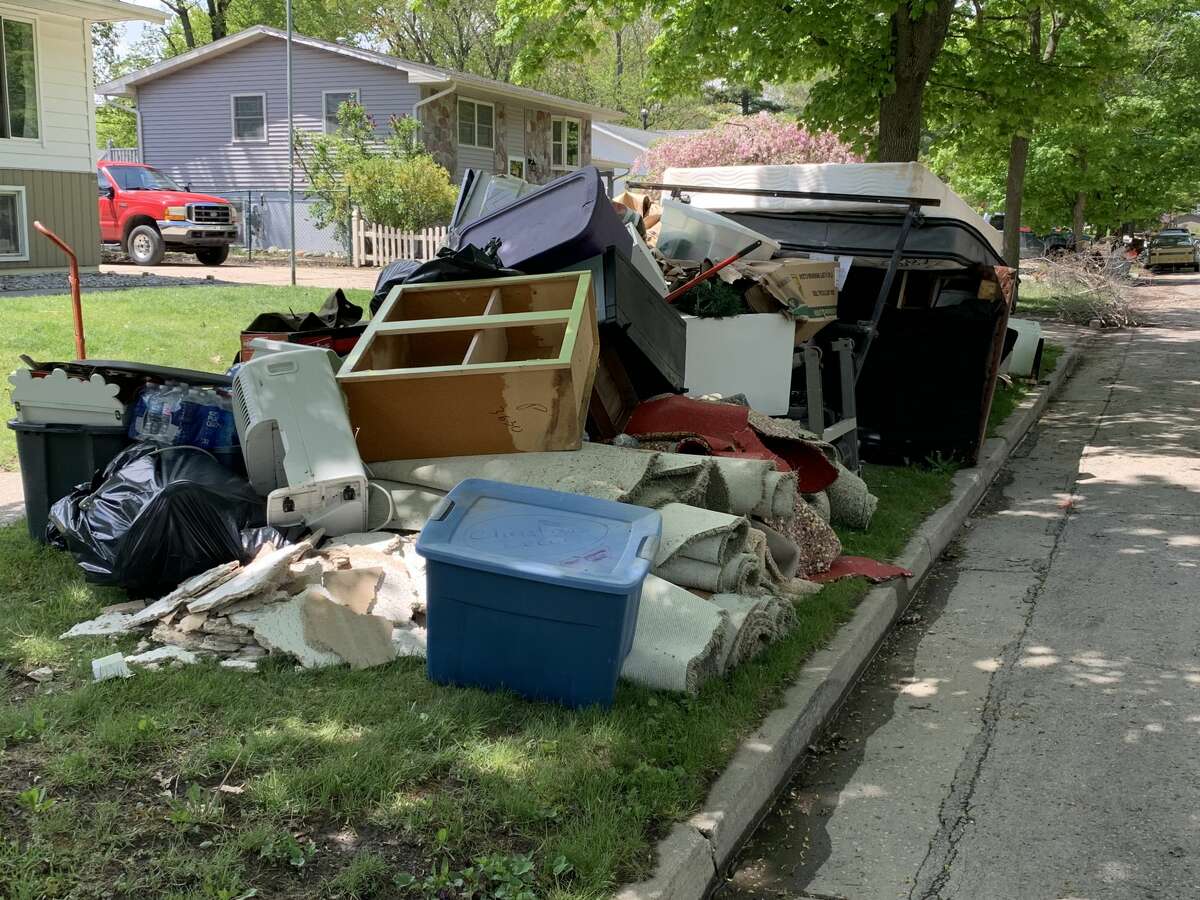 Piles of debris caused by flooded homes sit alongside the curb on Avon Street in Midland, Friday, May 22.