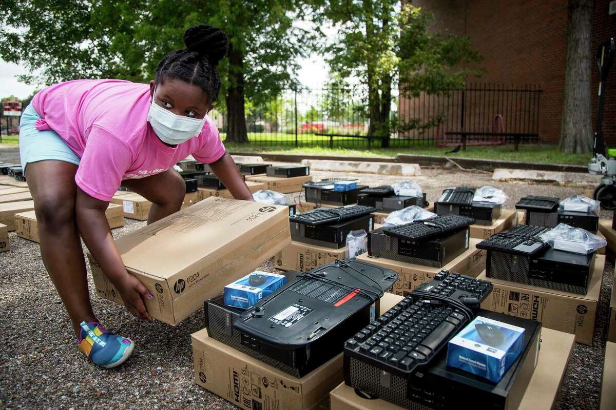 Volunteer Sloane Callander, 8, picks up a computer monitor as she helps distribute devices provided by the nonprofit Comp-U-Dopt on Thursday at Houston ISD’s Hogg Middle School. The novel coronavirus pandemic and subsequent shift to online-only learning has prompted a surge in demand for computers, which HISD hopes to fill in 2020-21 by providing a district-issued laptop to all students.