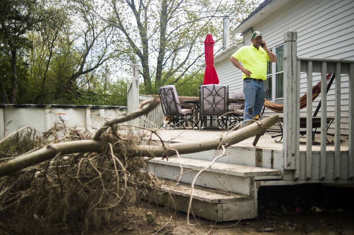 Matt McQuaid takes a phone call on his back porch while clearing belongings from his home on E. Pine River Road, which was devastated by flooding, Friday, May 22, 2020 in Midland. (Katy Kildee/kkildee@mdn.net)