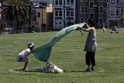 Liore Milgrom-Gartner and her daughter find a spot to place their blanket at Dolores Park in San Francisco.