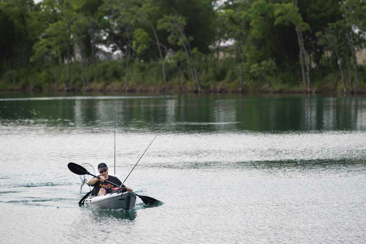 Drew Price paddles in to shore after fishing at Lake Friendswood Park on Friday, May 22, 2020 in Friendswood.