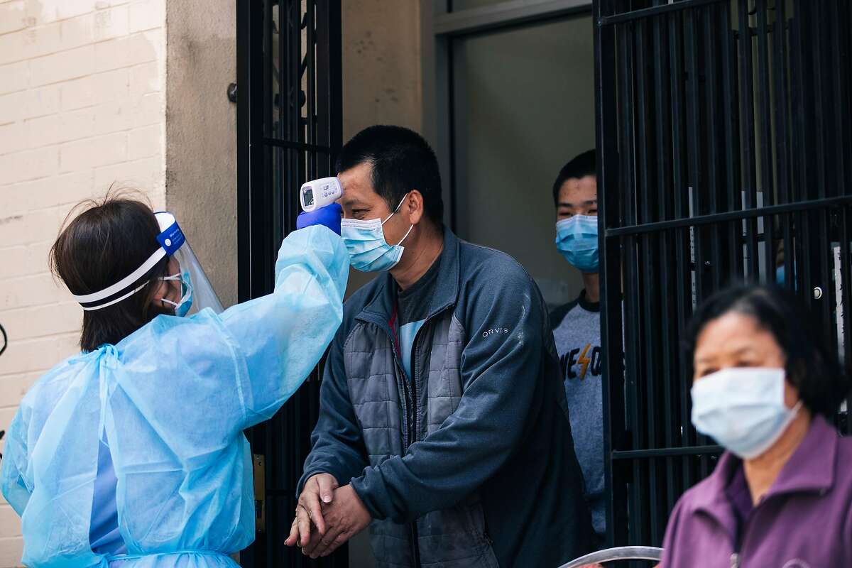 A resident from Hoy Sun Ning Yung Benevolent Association on Chinatown's Waverly Place undergoes a temperature check prior to receiving a test for the COVID-19 coronavirus disease during a joint pilot program with the Chinese Hospital and the San Francisco Department of Public Health in San Francisco, Calif. on Friday, May 22, 2020.