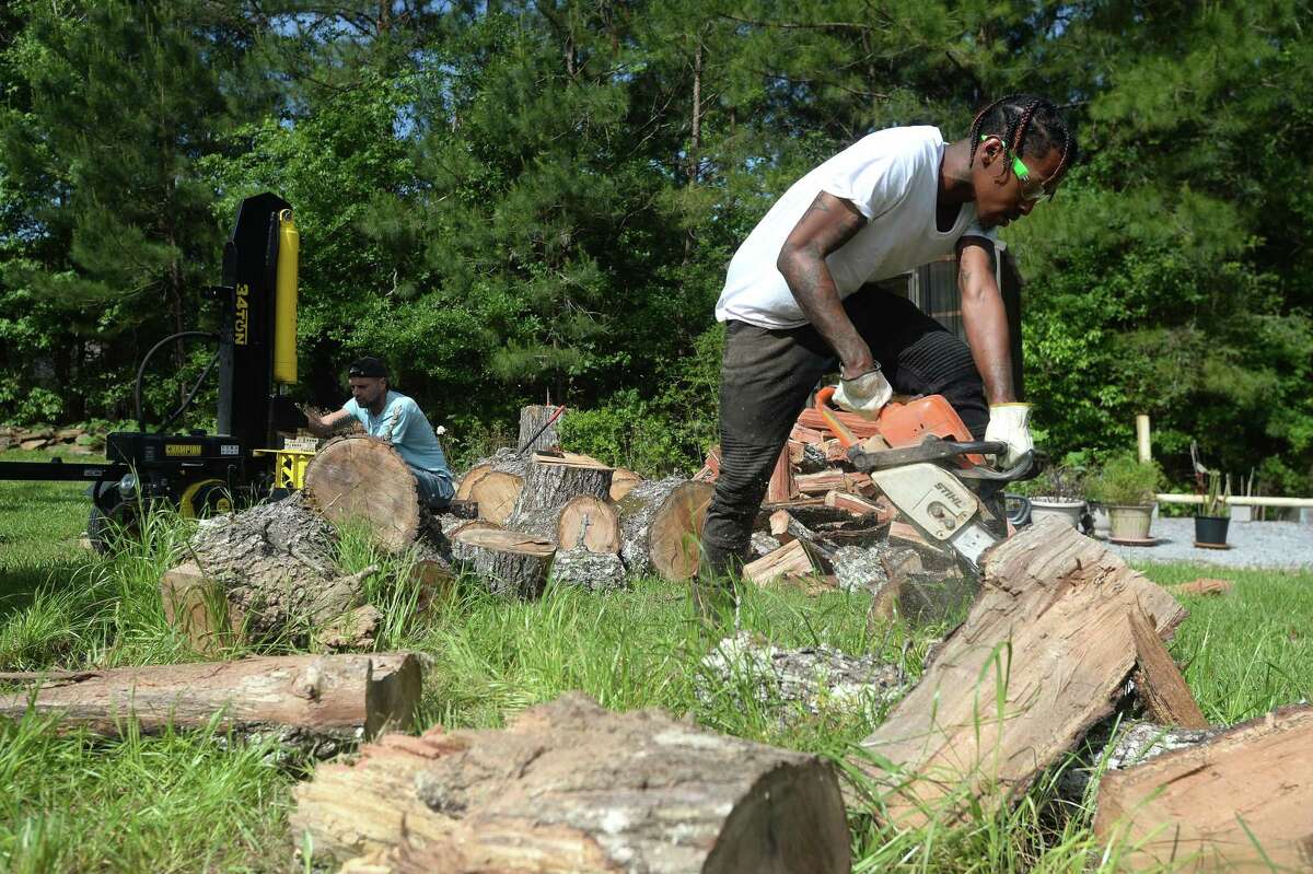 Josh Duncan splits wood from a cut red oak tree at Larry Shaw's home in Lumberton Monday, April 20, with help from his Reel Cajun restaurant co-worker Jamal Brown (foreground). Duncan has had a firewood side business, one of many he has developed over time, but is now relying on its income to help support he and teen son Jacob, since he and fellow restaurant workers were let go following restaurant closures amid COVID-19 restrictions. "I'm just a single father trying to make it," he says. Everyday he hustles to make ends meet, as calls to apply for unemployment have proved fruitless. Photo taken Monday, April 20, 2020 Kim Brent/The Enterprise
