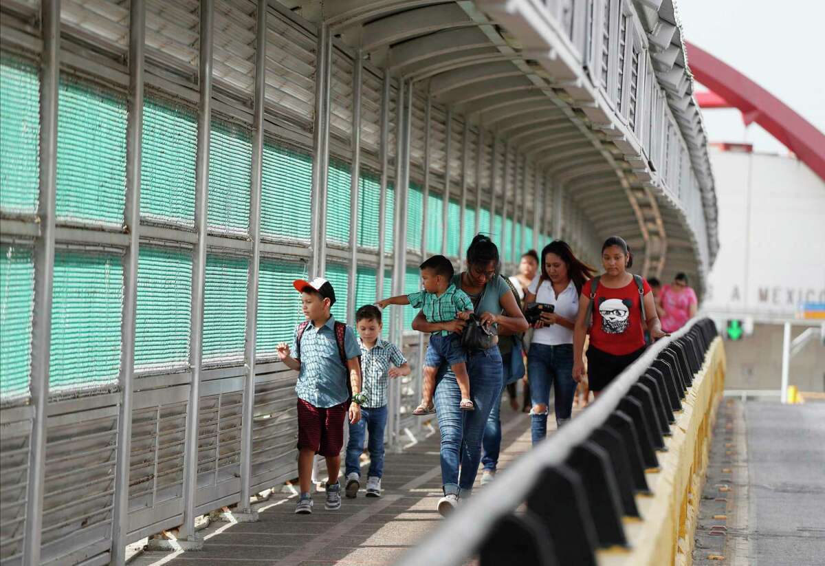 FILE - In this June 28, 2019 file photo, local residents with visas walk across the Puerta Mexico international bridge to enter the U.S., in Matamoros, Tamaulipas state, Mexico.