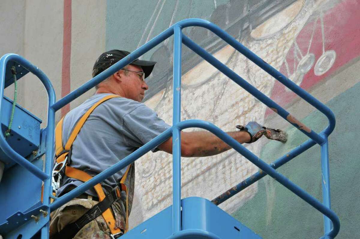 Muralist Kevin Clark works on a mural of the Troy Savings Bank Music Hall above the parking lot adjacent to the music hall and bank in Troy. (Lori Van Buren / Times Union)
