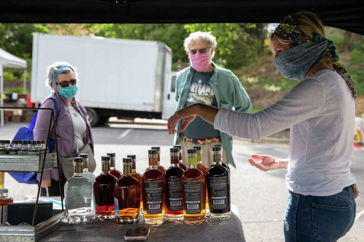 Jaime Windon, the CEO and founder of Windon Distilling, sells her rum to Doyle Niemann and his wife Karen Morrill at the Riverdale Park Farmers Market in Riverdale Park, Md.