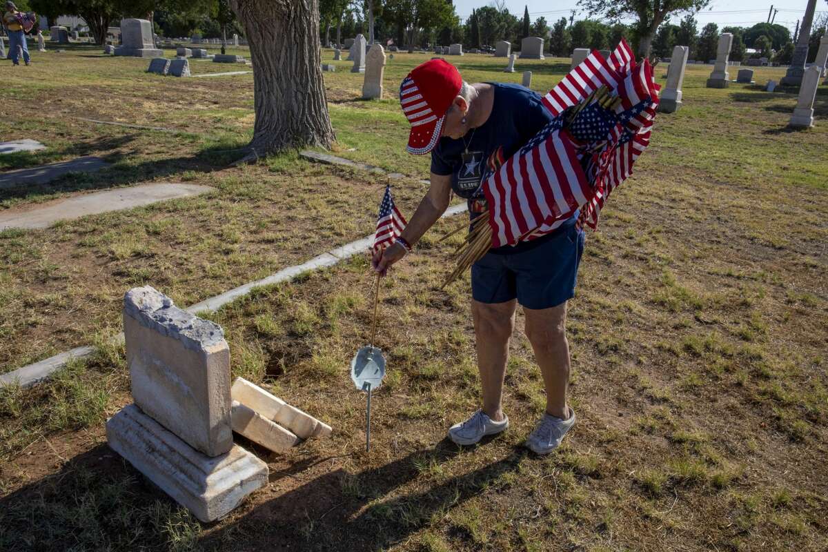Karyn Basse places a flag on a veteran?•s grave Saturday, May 23, 2020 at Fairview Cemetery. Jacy Lewis/Reporter-Telegram