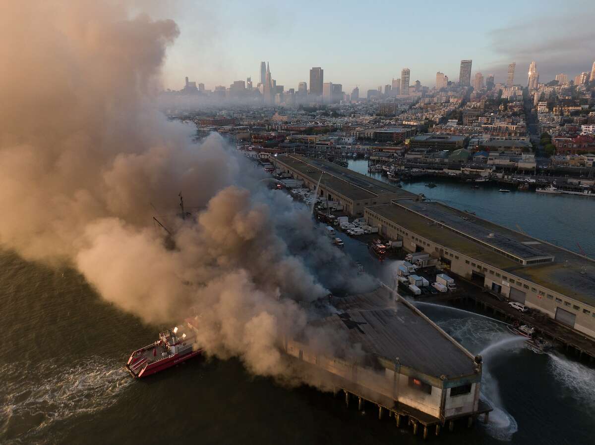Firefighters spray water on Pier 45 4-alarm that began in the warehouse early on Saturday, May 23, 2020, in San Francisco, Calif. The SS Jeremiah O'Brien is docked next to this pier.