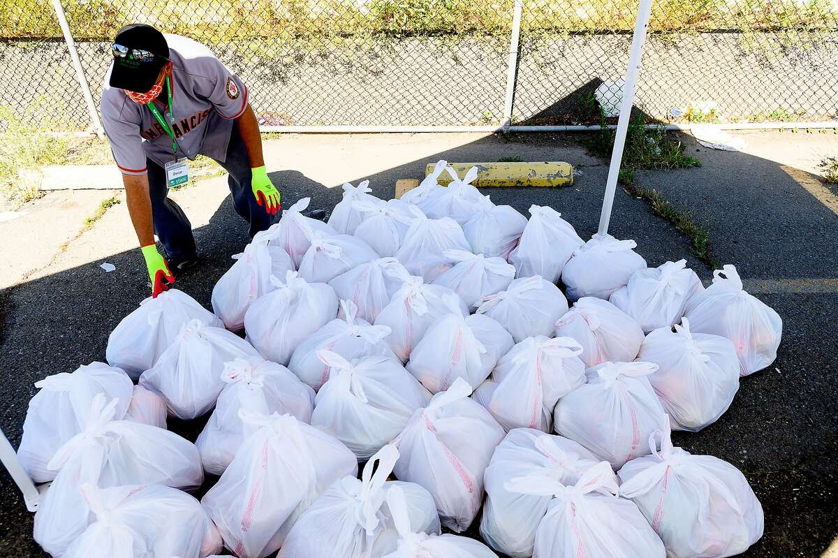 Oscar Platero, a staff member with the San Francisco-Marin Food Bank, sorts food bundles during a distribution event on Saturday, May 23, 2020, in San Francisco.