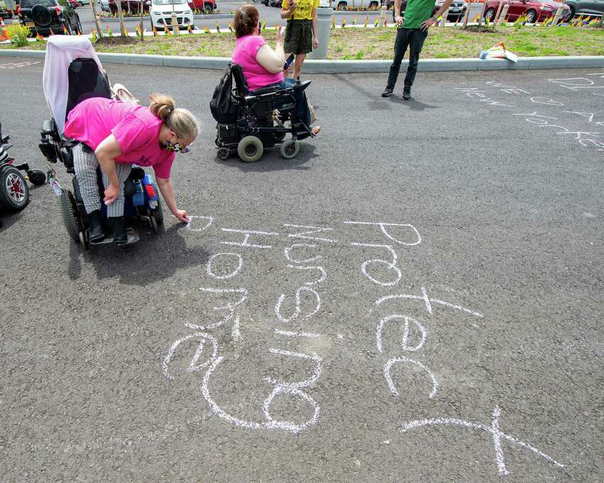 Julie Farrar writes a message on on the driveway leading to the Shaker Place Rehabilitation and Nursing Center in Colonie during a vigil held by ADAPT Capital Region on Saturday, May 23, 2020 calling on New York state to support nursing home workers, transfer residents who so choose to safer settings and step up state regulations of nursing homes (Jim Franco/Special to the Times Union.)
