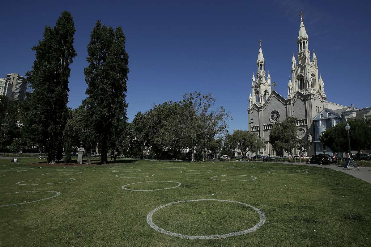 Circles designed to help prevent the spread of the coronavirus by encouraging social distancing are shown at Washington Square park in front of Saints Peter and Paul Church in San Francisco, Saturday, May 23, 2020. (AP Photo/Jeff Chiu)