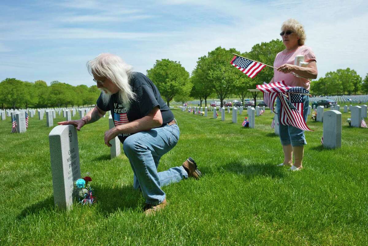 Navy veteran Donald Amorosi, left, and his wife Sharon Amorosi of South Glens Falls place a flag and flowers at the grave of Army veteran Chad Byrne at the Gerald B.H. Solomon Saratoga National Cemetery on Sunday, May 24, 2020, in Schuylerville, N.Y. The Amorosis visit 15 graves of friends and the children of friends. The couple has been doing this for over 14 years. Donald Amorosi served during Vietnam. Amorosi met Byrne in 2008, just before his death. (Paul Buckowski/Times Union)