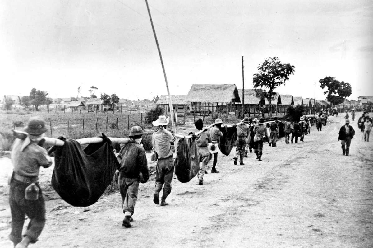 A photo released by the U.S. military in 1945, taken from the Japanese, shows prisoners of war in the Philippines carrying their comrades in slings, described as dead and wounded during the Bataan Death March in 1942. Subsequent information from military archivists and surviving prisoners strongly suggests the photo may actually depict a burial detail at Camp O’Donnell, the camp where they were held after the march. (AP Photo/U.S. Marine Corps)