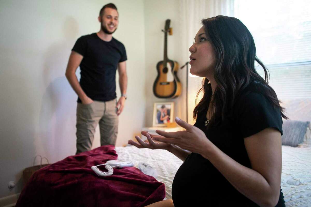 Marissa Mayberry, 28, talks as she sits on her bed and her husband Matthew, 28, listens at their home in Hondo, Texas on May 19, 2020. Marissa usually drives an hour each way to her midwife for prenatal care but has now been given the medical equipment, such as blood pressure cuffs, urine sticks and dopplers, to do it herself until the last few weeks of her pregnancy.
