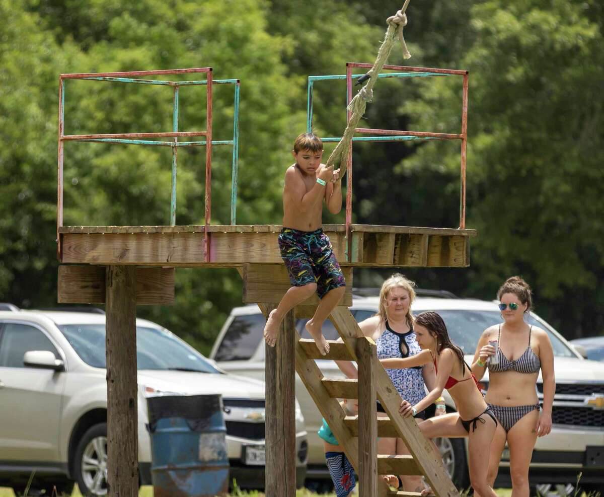 A visitor at Chadillac’s Ranch in Conroe hangs off a rope that lands in a lake for Memorial Day weekend, Sunday, May 24, 2020. Chadillac’s Ranch postponed their usual Spring Break opening until Memorial Day weekend with restrictions.