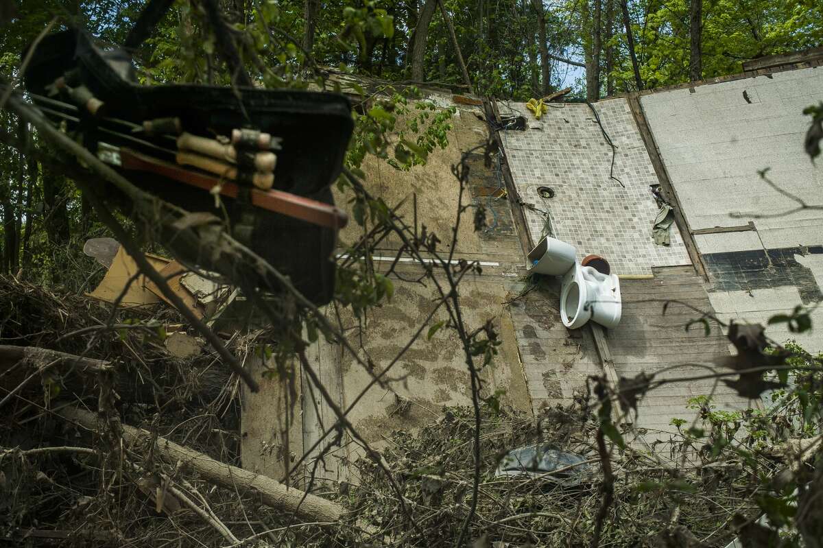 The floor of a home leans against trees as a tool belt and other debris hang from tree branches Monday, May 25, 2020 in downtown Sanford. (Katy Kildee/kkildee@mdn.net)