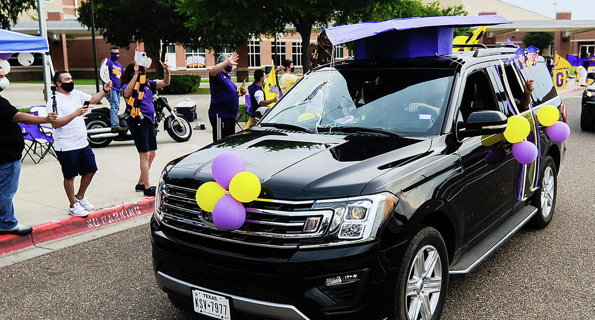 Lyndon B. Johnson High School graduating seniors, driven by friends and family, ride past the front of the school as faculty members cheer them on, Saturday, May 23, 2020, as the students participate in a parade in lieu of their prom.