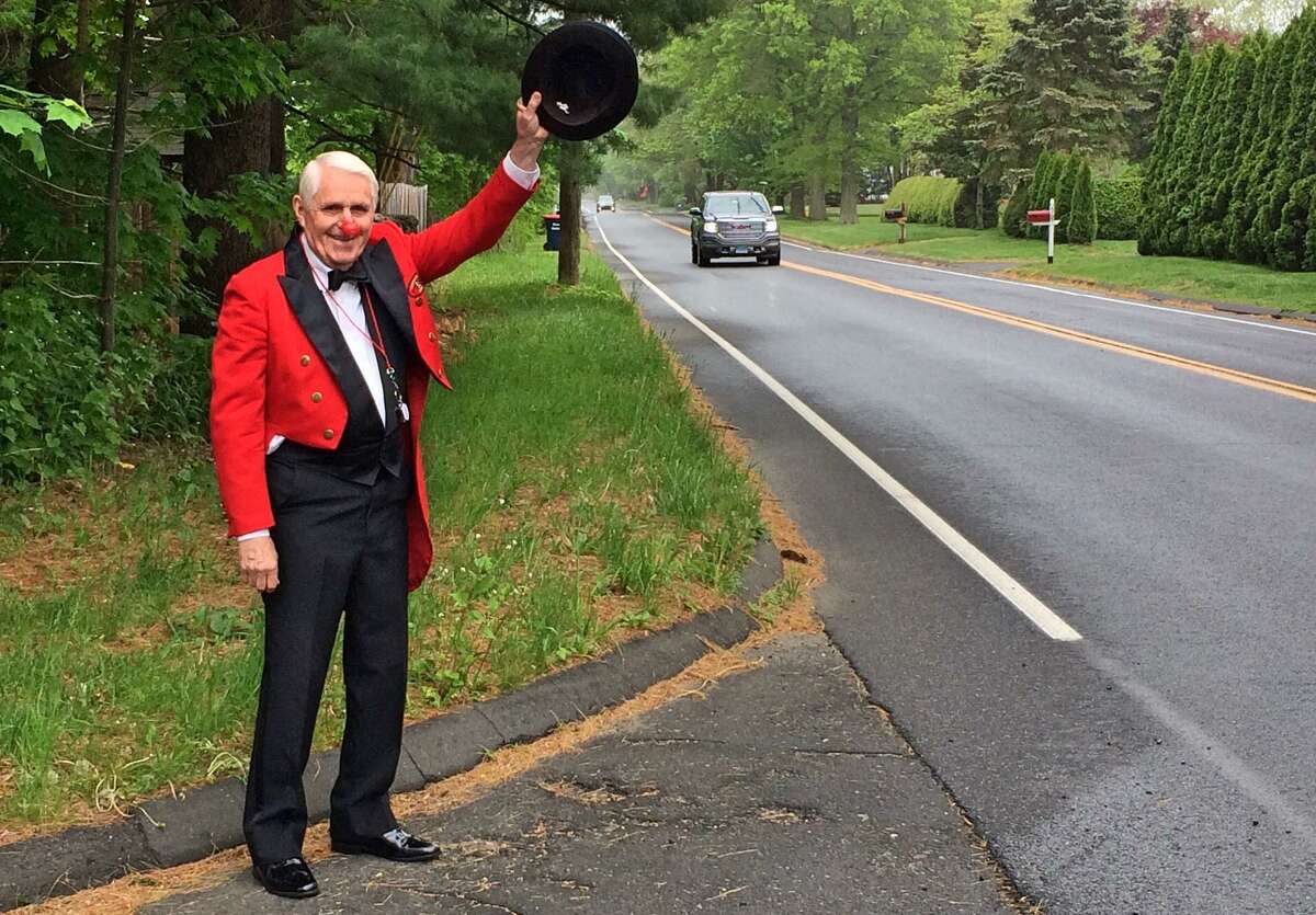Trumbull resident William Murphy, wearing his 1992 Barnum Festival Ringmaster attire, waves to passing traffic at noon on Memorial Day during the town's one-minute noise salute to veterans and emergency responders.